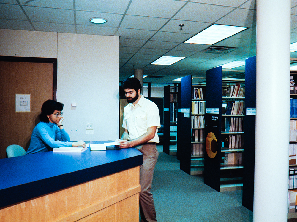 person standing at desk in library